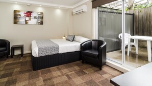 Une chambre à coucher avec un lit, une chaise, une petite table et un tableau accroché au mur.