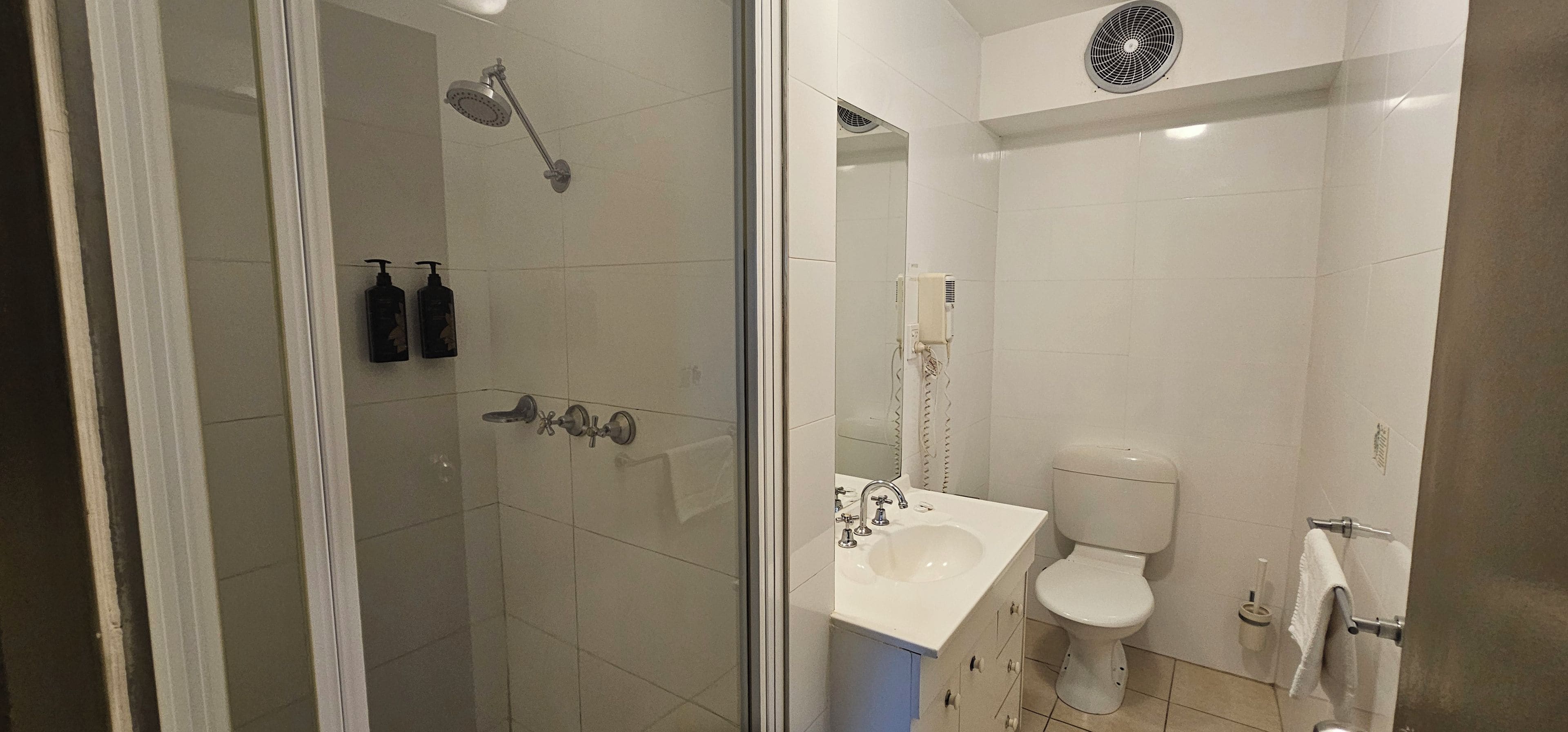 A modern bathroom with a glass shower enclosure, a toilet, and a sink.