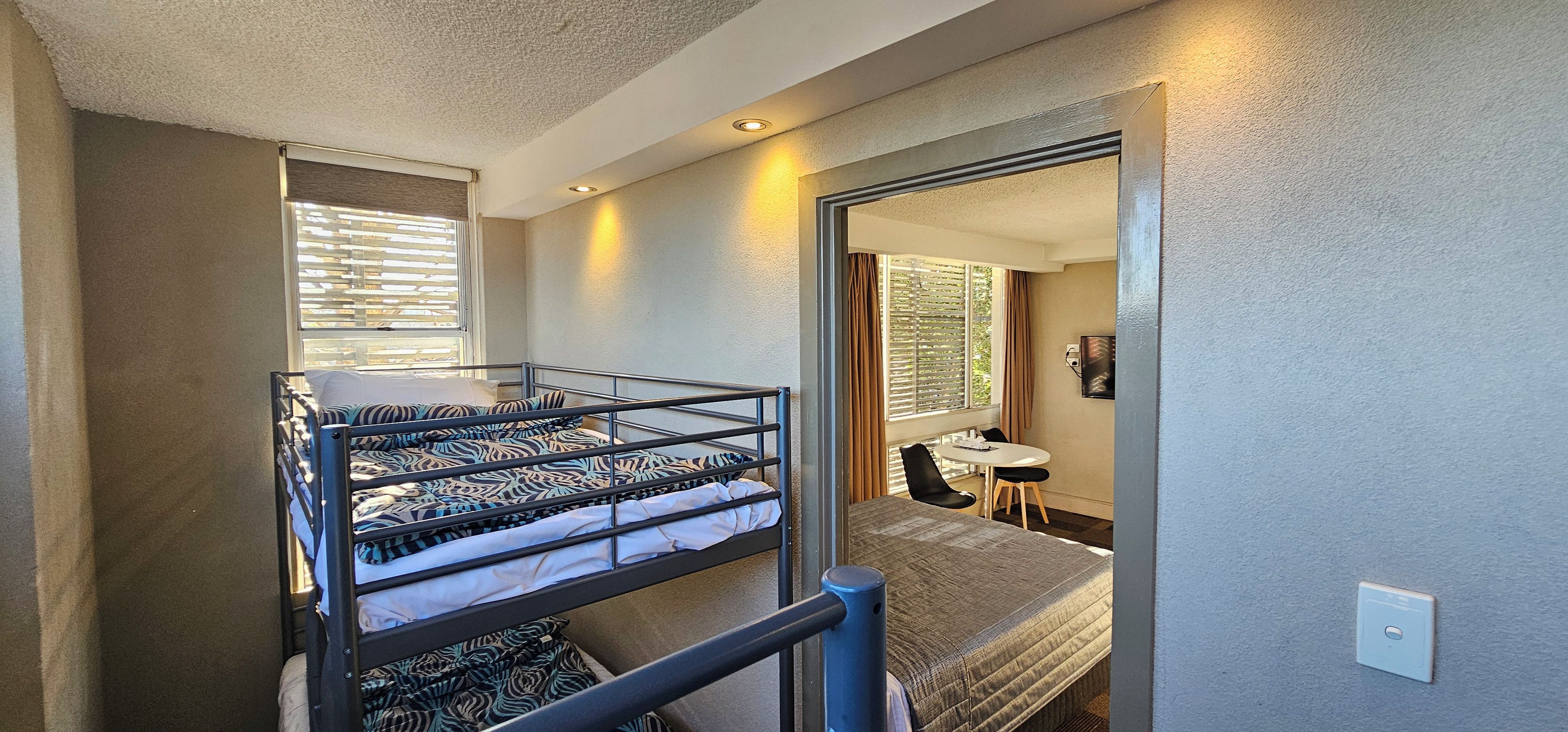 Habitación pequeña con una cama individual superpuesta, una mesita y una silla.