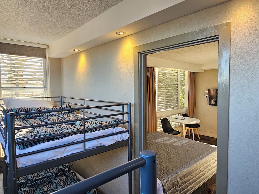 A compact room with a bunk bed, a small table, and a chair.