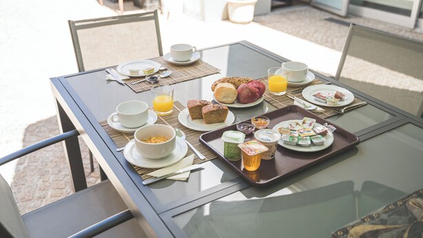 A breakfast table with plates of food, cups, and a tray of condiments. - Hotel de Cerva (Ribeira de Pena)