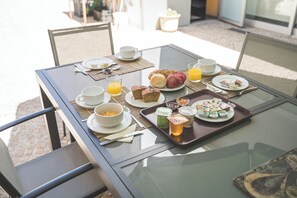 A breakfast table with plates of food, cups, and a tray of condiments.
