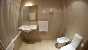 A bathroom with a sink, mirror, towel rack, toilet, and shower curtain.