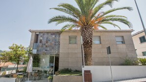 A hotel with a tiled facade, outdoor seating, and a palm tree. - Hotel de Cerva (Ribeira de Pena)