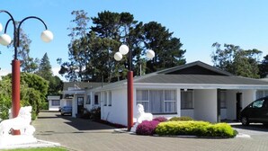 Un motel de una sola planta con fachada blanca, una entrada cubierta y una estatua de un caballo.