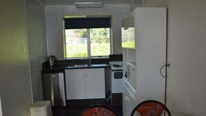 Una cocina compacta con ventana, un lavamanos, una estufa y un refrigerador.