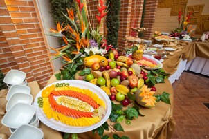 Una mesa de buffet con una variedad de frutas y verduras, como manzanas, plátanos y zanahorias, dispuestas en un diseño decorativo.