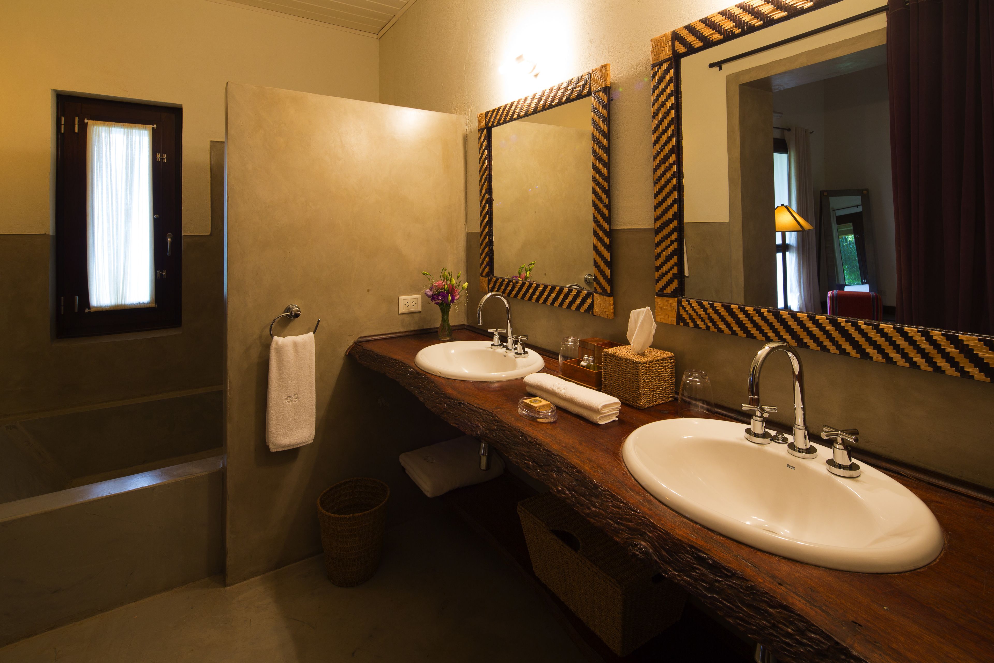 A bathroom with two sinks, a mirror, a towel rack, and a window with curtains.
