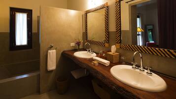 A bathroom with two sinks, a mirror, a towel rack, and a window with curtains.