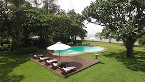 A backyard with a swimming pool, surrounded by lush greenery and trees.