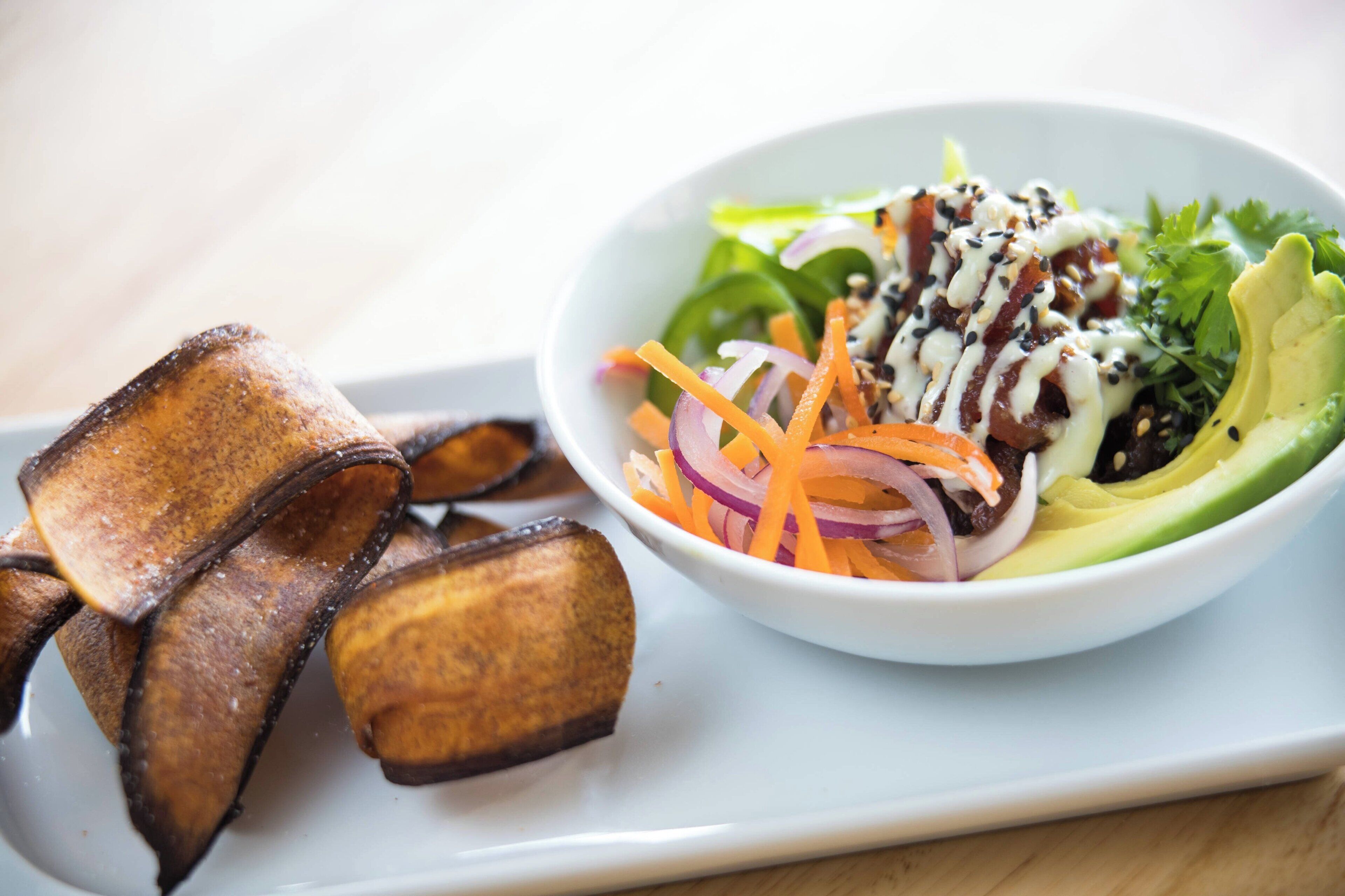 A white plate with a salad and fried plantains.