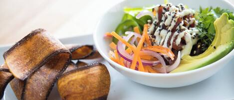 A white plate with a salad and fried plantains.