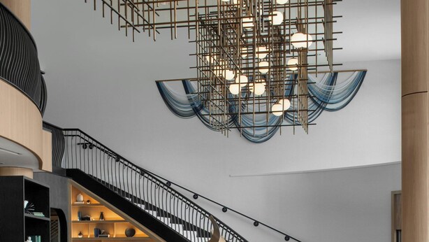 A modern lobby with a central circular seating area, a staircase, and a unique hanging light fixture. - Renaissance Raleigh North Hills Hotel (Raleigh)