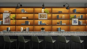 A modern bar area with a marble countertop, green bar stools, and a wooden bookshelf with books and decorative items. - Renaissance Raleigh North Hills Hotel (Raleigh)