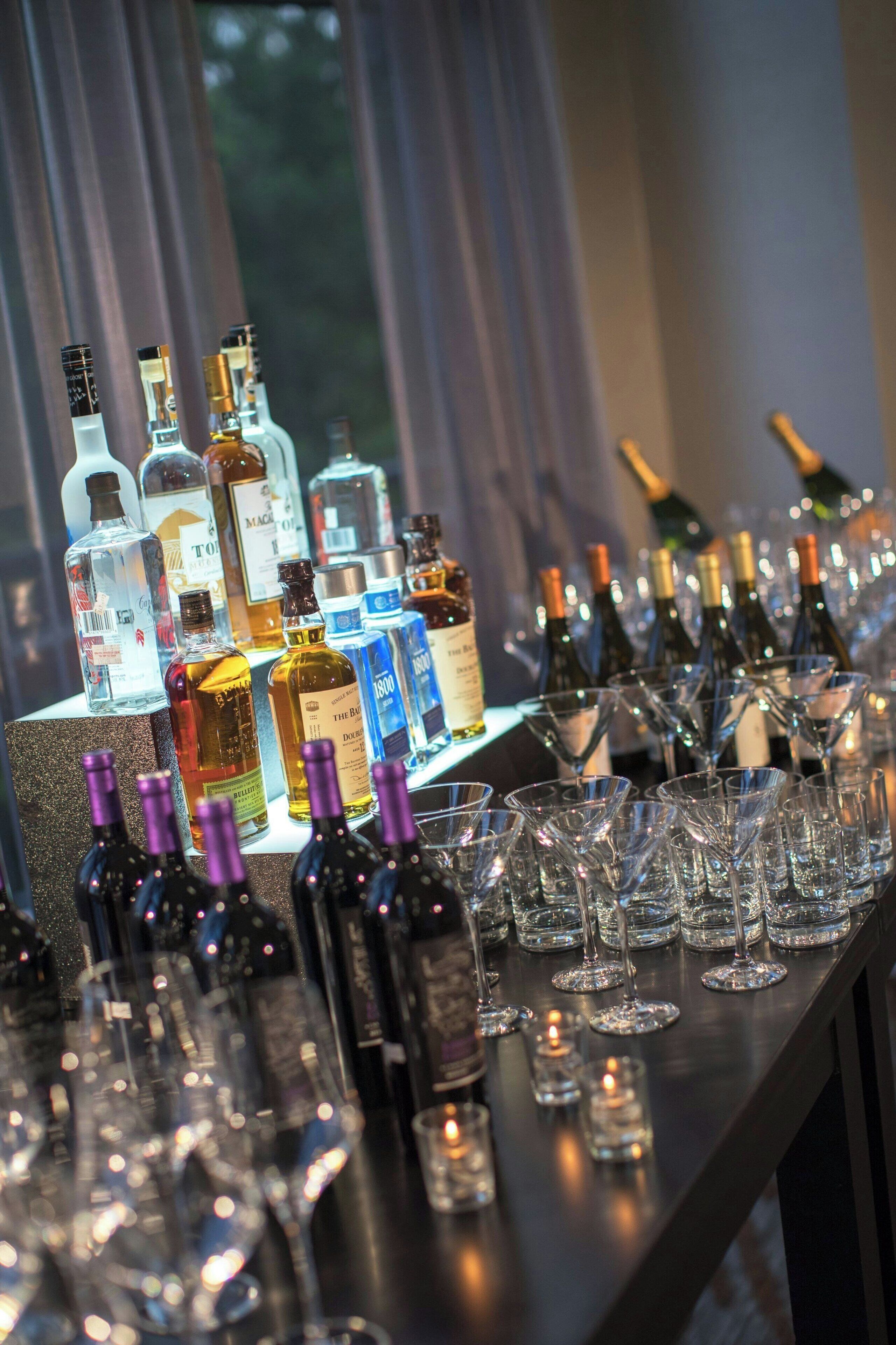 Una zona de bar con varias botellas de licores y vasos dispuestos sobre una barra.