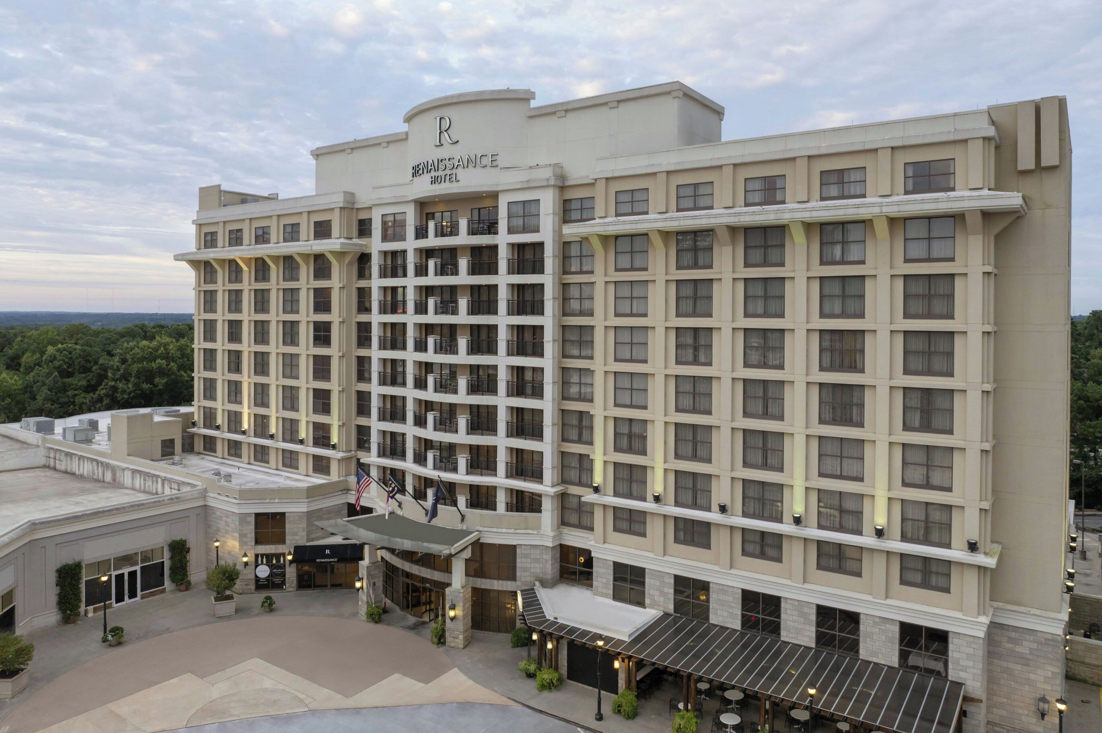 Un Renaissance Hotel con facciata moderna, numerosi balconi e una zona esterna coperta con posti a sedere.