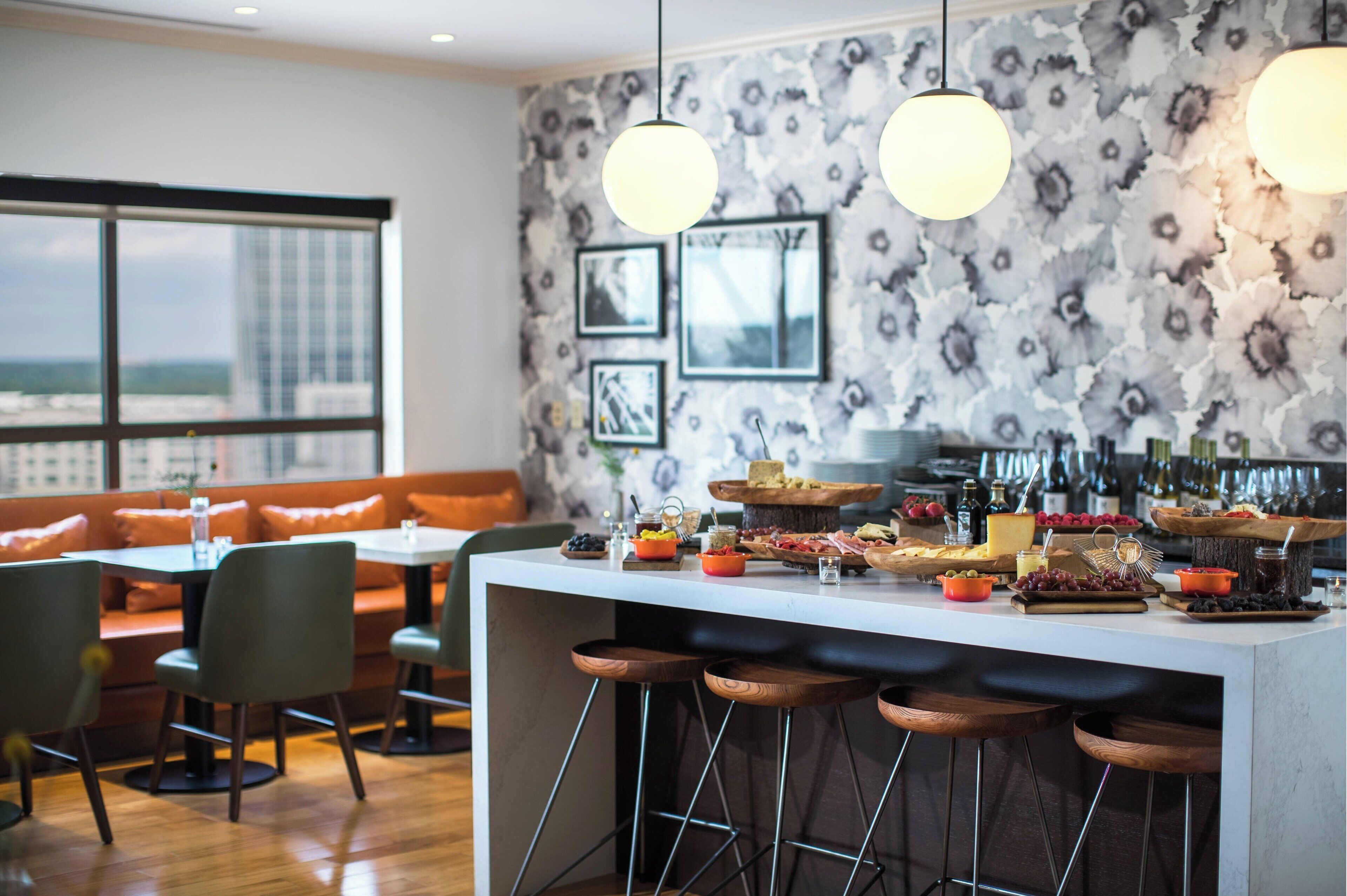 A modern bar area with a central island featuring a variety of food and drink options, surrounded by seating.