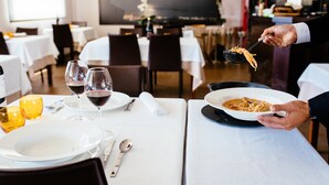A restaurant setting with tables set for dining, wine glasses, and a person serving food. - Hotel L'Algadir del Delta (Amposta)
