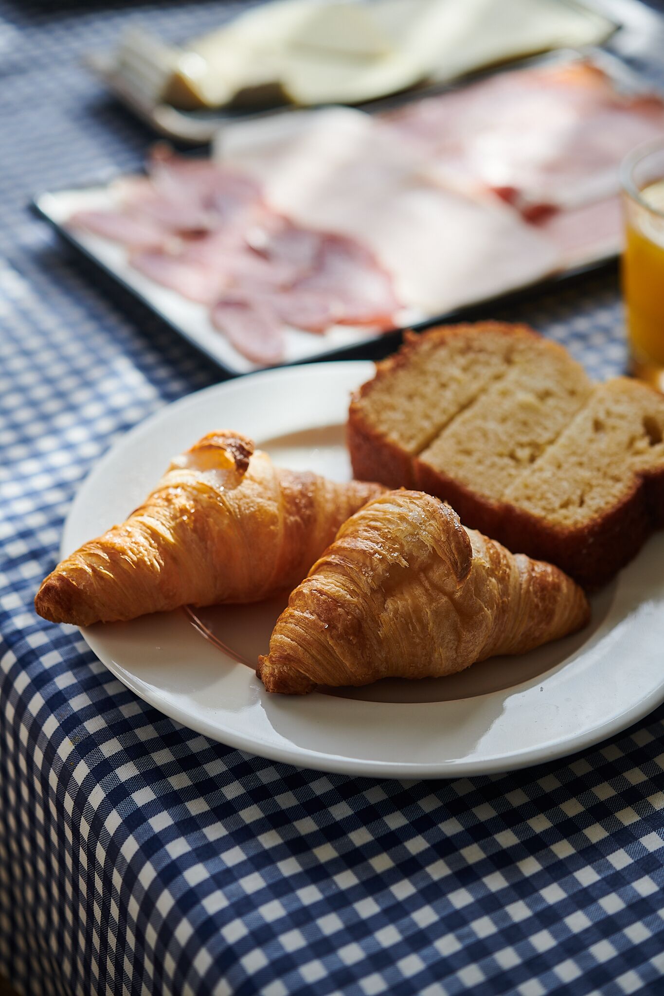 A plate with croissants and bread on a checkered tablecloth.