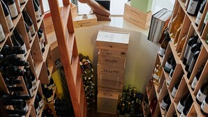 A wine cellar with wooden shelves and boxes, a staircase, and a view of the street outside. - Hotel L'Algadir del Delta (Amposta)