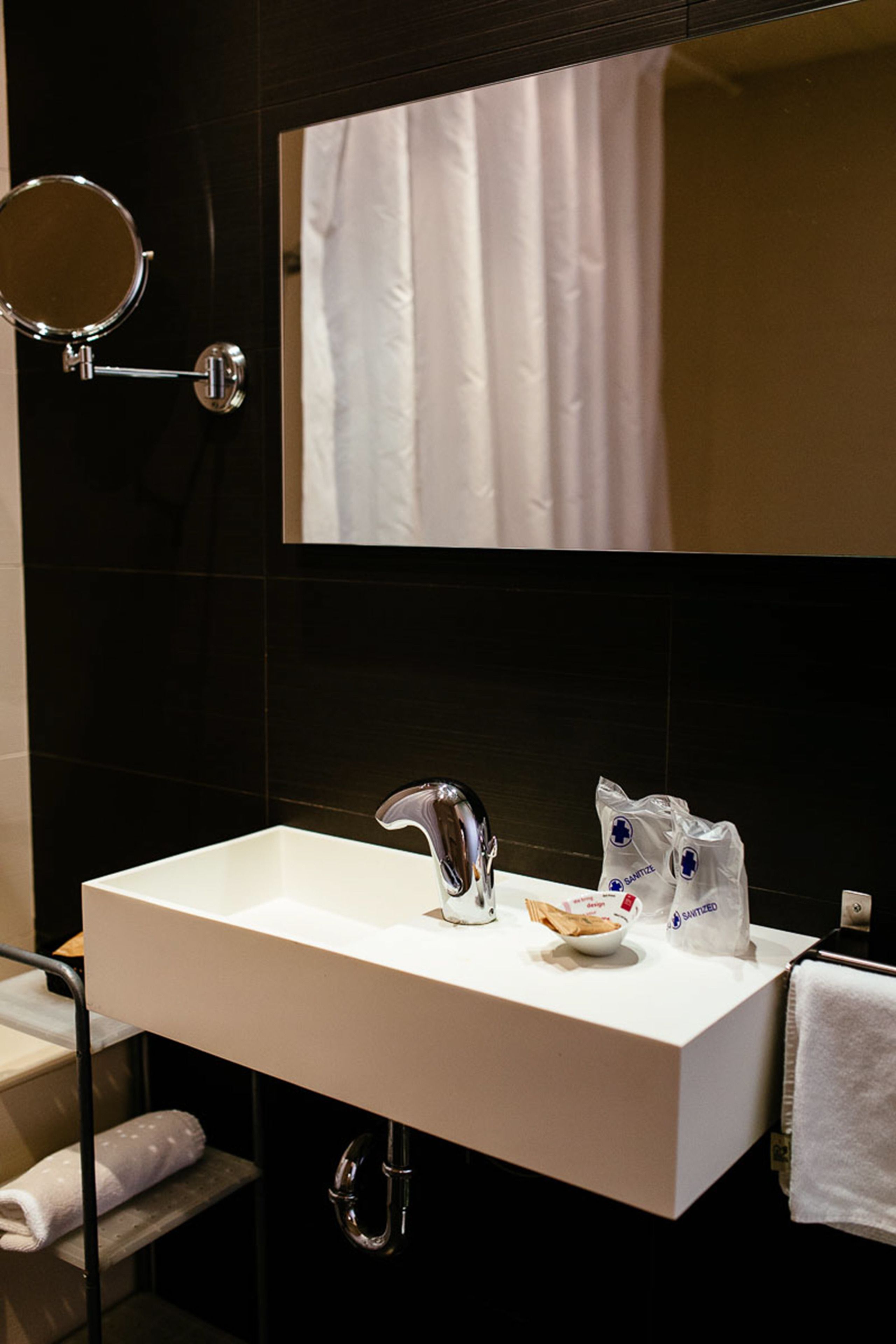 A modern bathroom with a white sink, a mirror, and a towel rack.