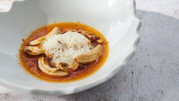 A white bowl with a sauce and sliced onions on a textured surface.