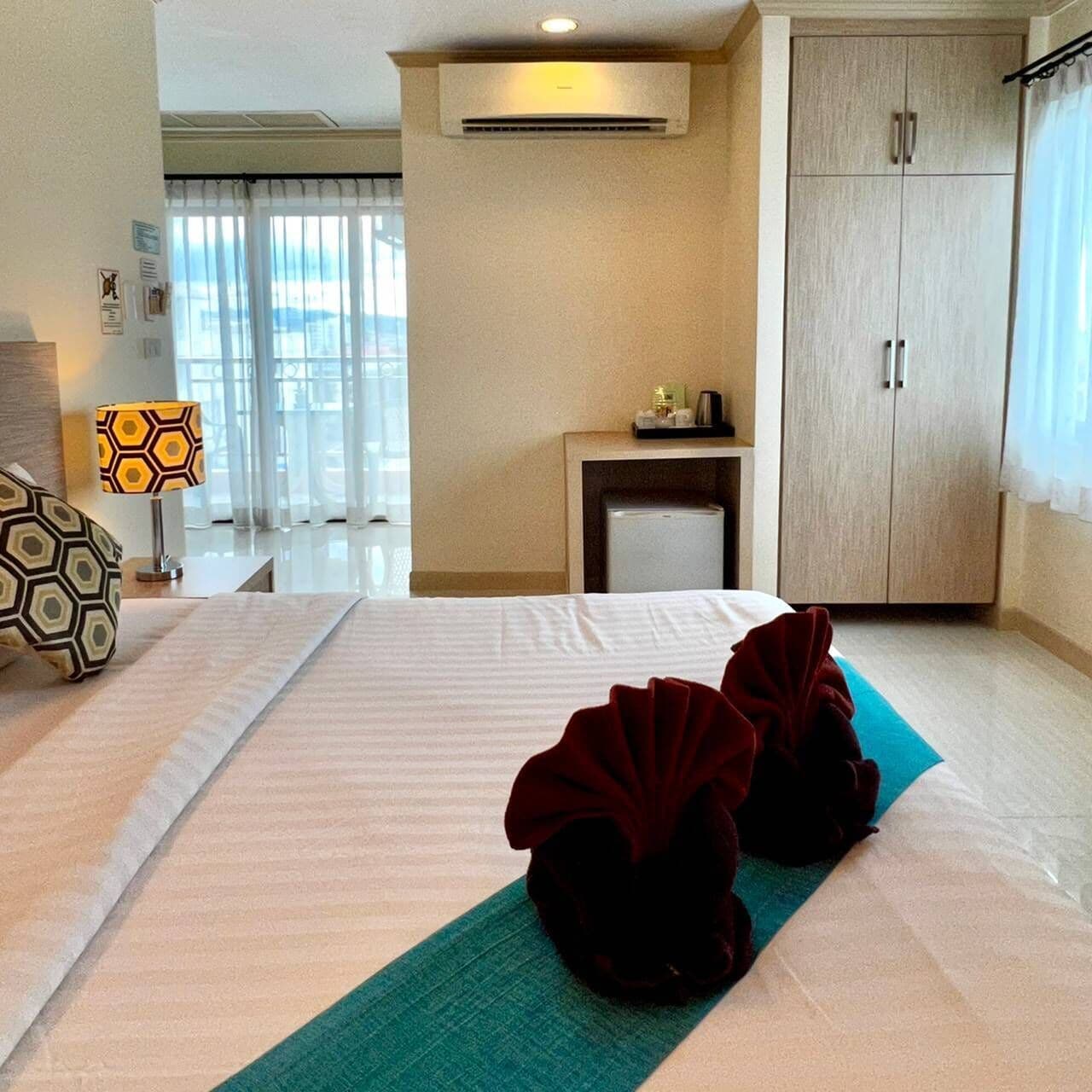 A hotel room with a bed, a desk, a lamp, and a wardrobe.