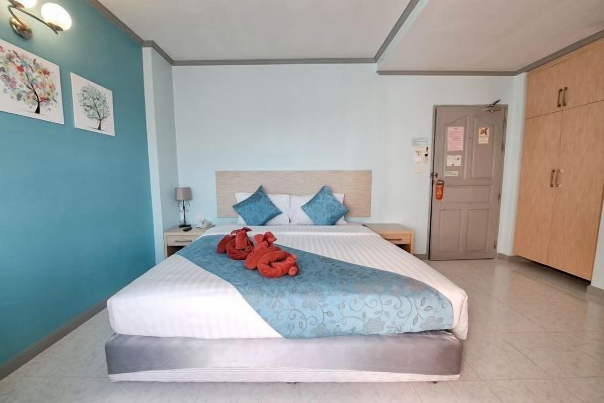 Une chambre d’hôtel comprenant un lit, une table de chevet, une lampe, une armoire et deux œuvres d’art murales.
