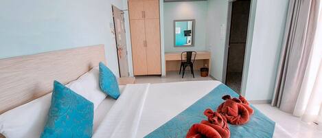 A hotel room with a bed, a desk, a chair, and a wardrobe.