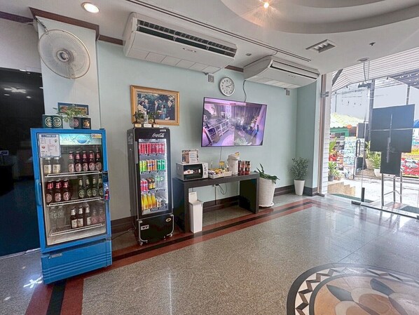 A lobby with a vending machine, a clock, a television, and a view of the outside.