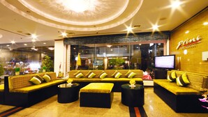 A modern lounge area with a sofa set, a flat-screen TV, and a ceiling light fixture. - Thipurai city hotel (Hua Hin)