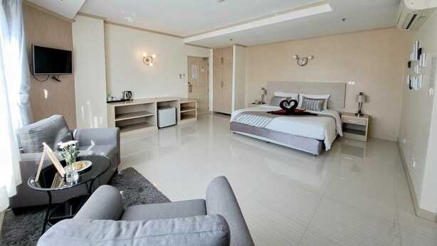 A modern hotel room with a large bed, a sofa, a TV, and a desk area. - Thipurai city hotel (Hua Hin)