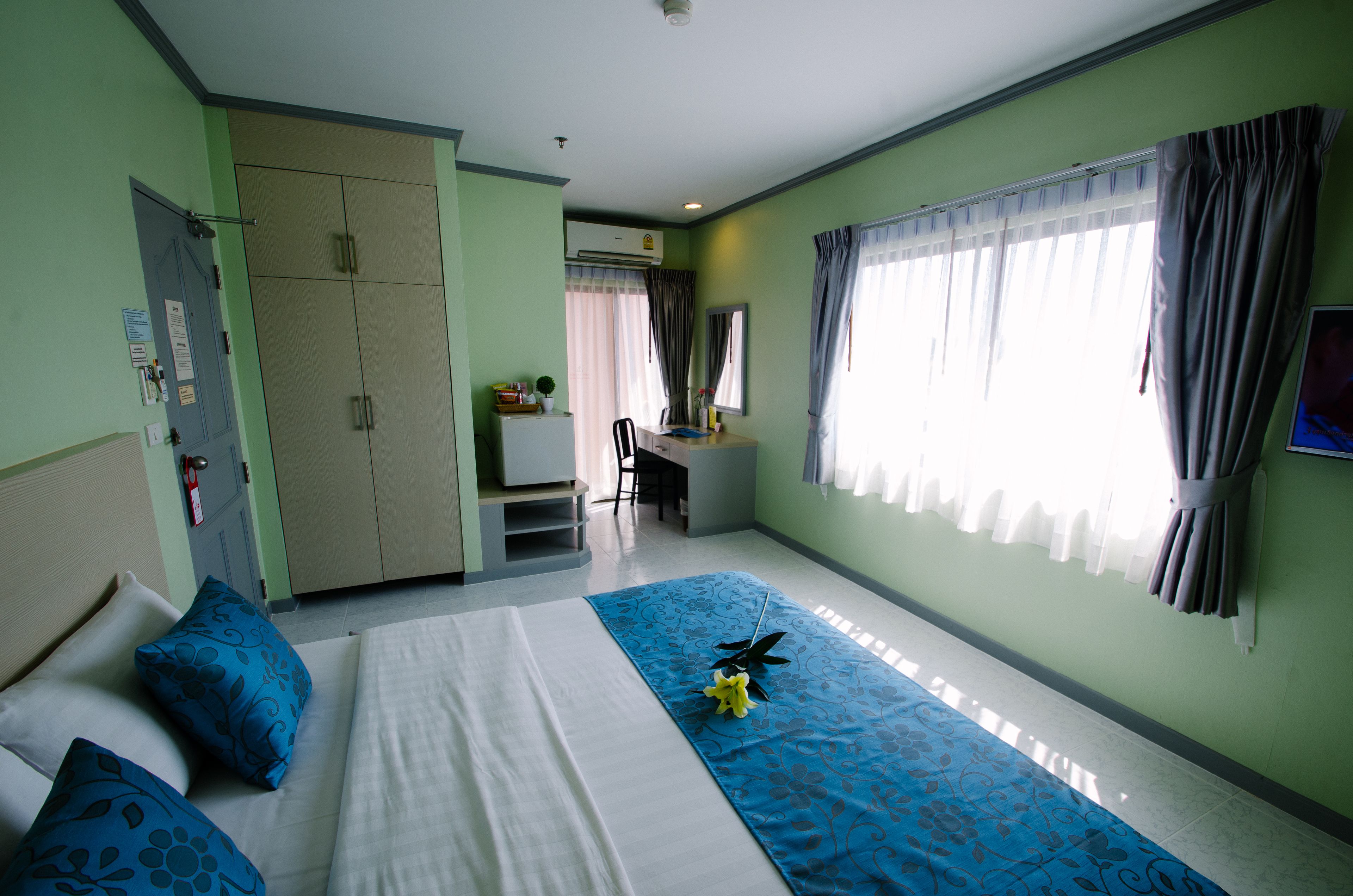 A hotel room with a bed, a desk, a chair, and a wardrobe.
