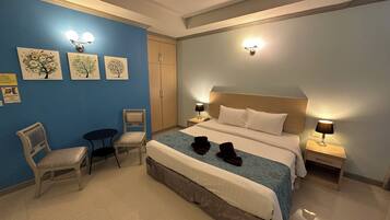 A hotel room with a bed, two bedside tables, a chair, a desk, and a wardrobe.