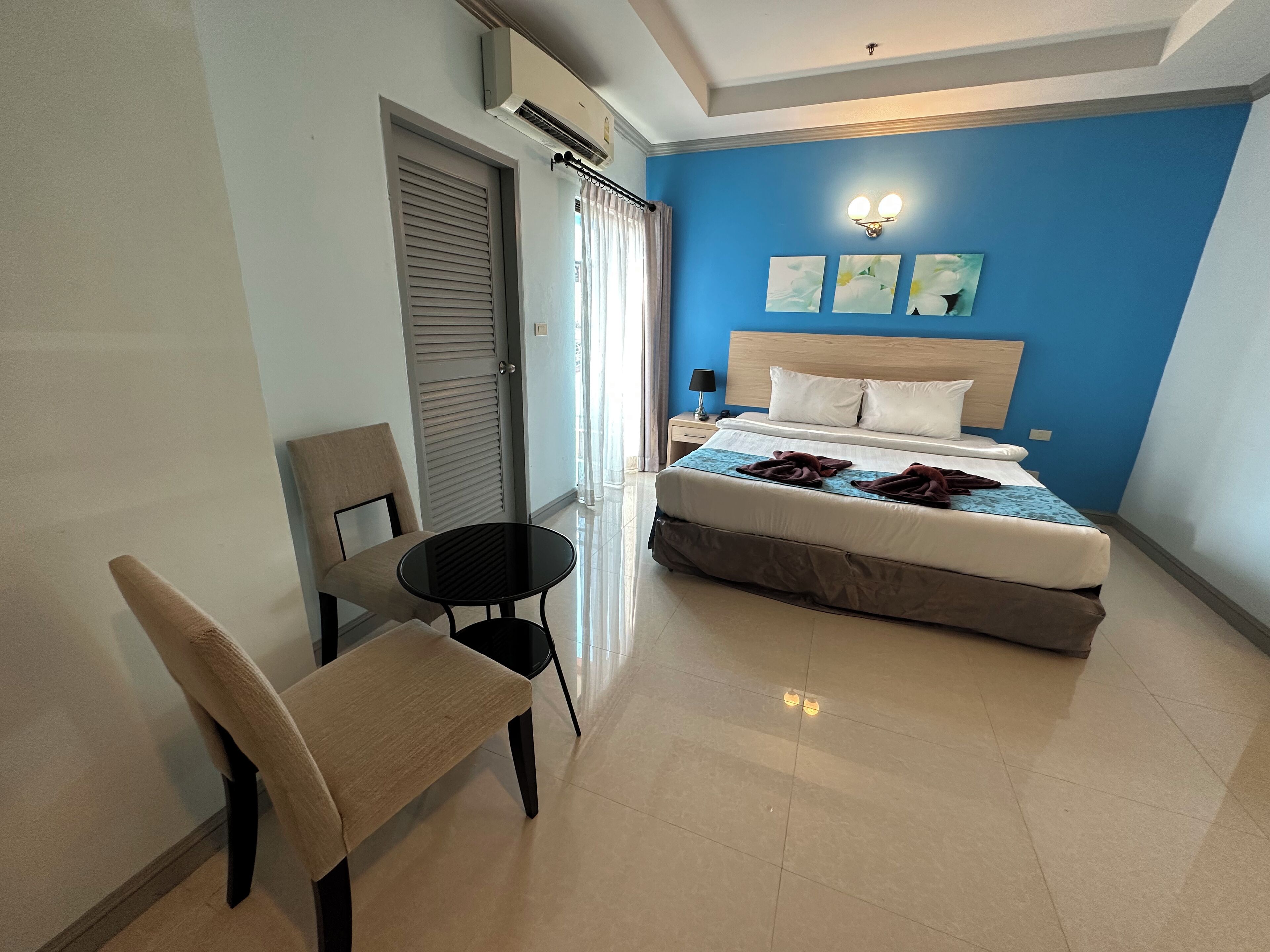 A hotel room with a bed, a chair, a table, and a nightstand.