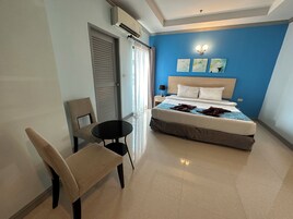 A hotel room with a bed, a chair, a table, and a nightstand.