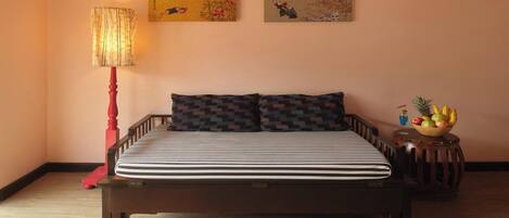 Un dormitorio con cama, mesita de noche, lámpara y dos obras de arte en las paredes.