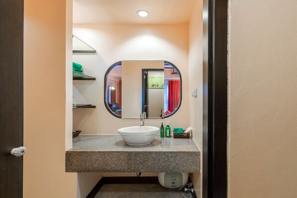 Un baño con lavamanos blanco, espejo y toallero.