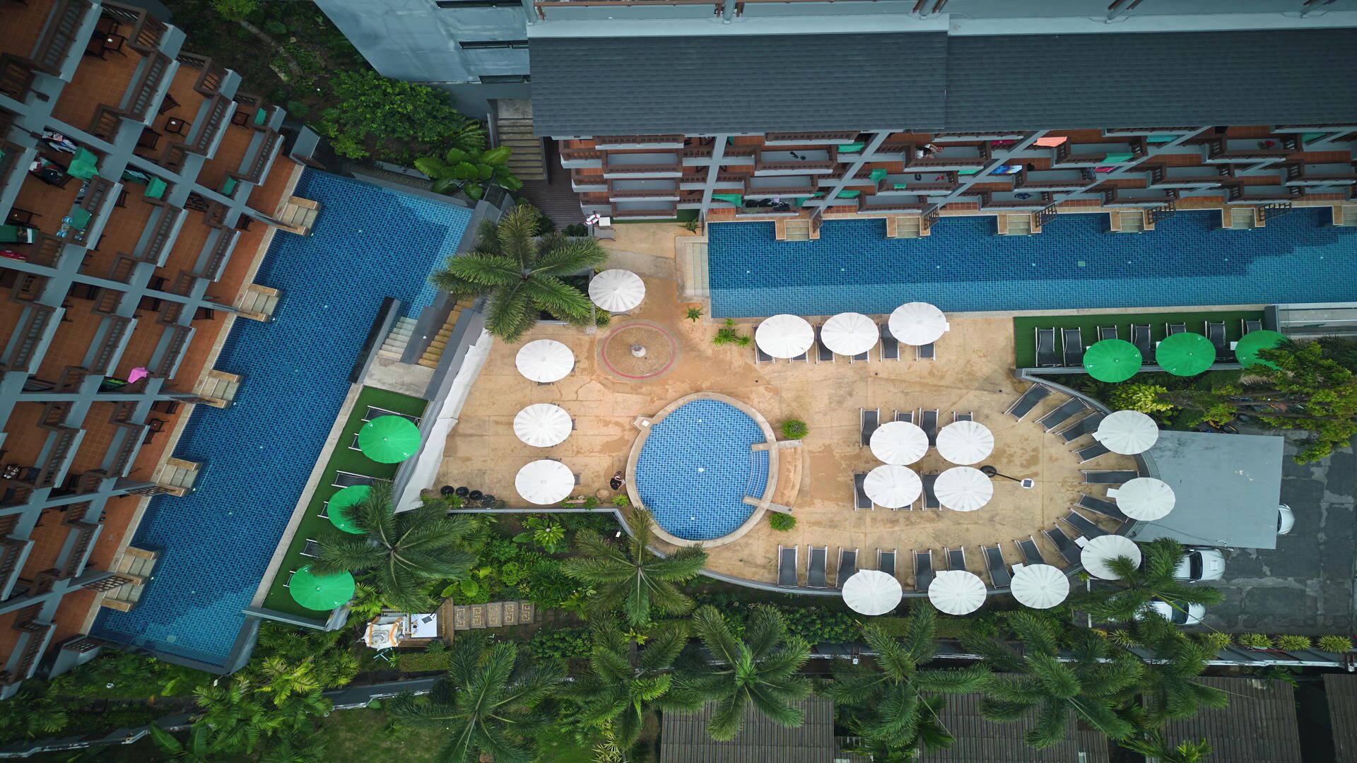 Vista aérea de un hotel con varias piscinas, zonas de estar al aire libre y abundante vegetación.