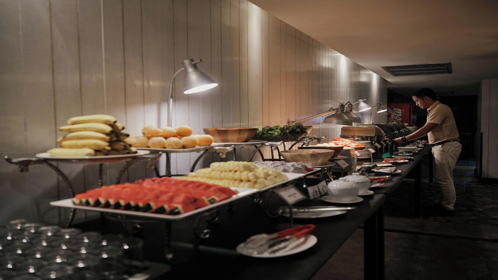 Un buffet proposant une variété de plats, avec un membre du personnel qui sert les clients.