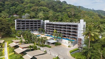 Un resort con edificios de varios pisos, una piscina central y abundante vegetación que rodea la propiedad.