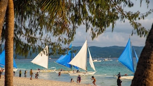 Una playa con barcos y gente.