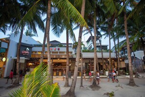 A beachfront area with palm trees, a restaurant, and a building with a sign. - Crown Regency Beach Resort (Boracay Island)