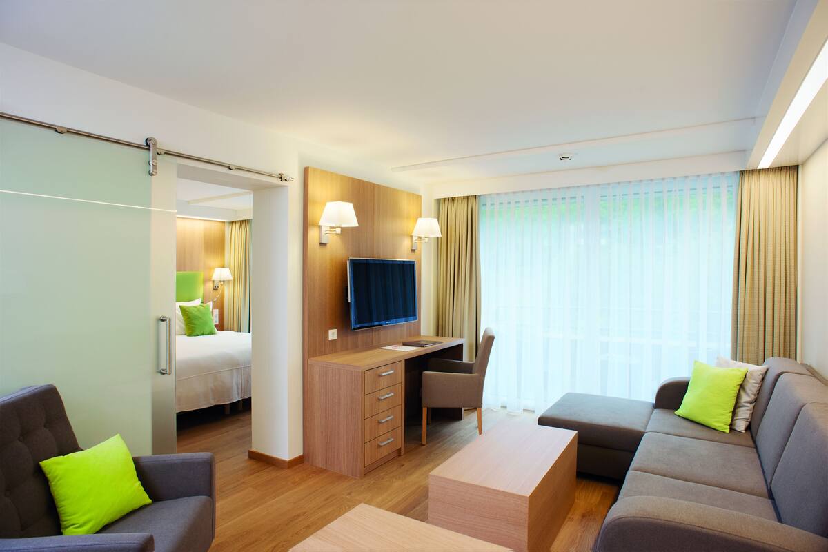 Una habitación de hotel con cama, escritorio, televisor, sofá y sillón.