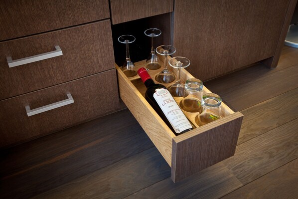 A wooden drawer with a bottle of wine, glasses, and a wine label.