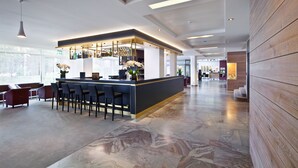 A modern bar area with a marble floor, bar stools, and a counter with bottles.