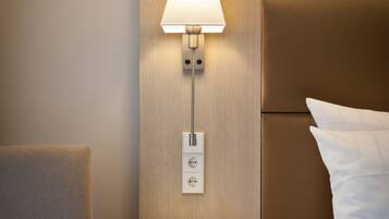 Une chambre d’hôtel avec une table de chevet, une lampe, une chaise et un lit avec du linge de lit blanc.