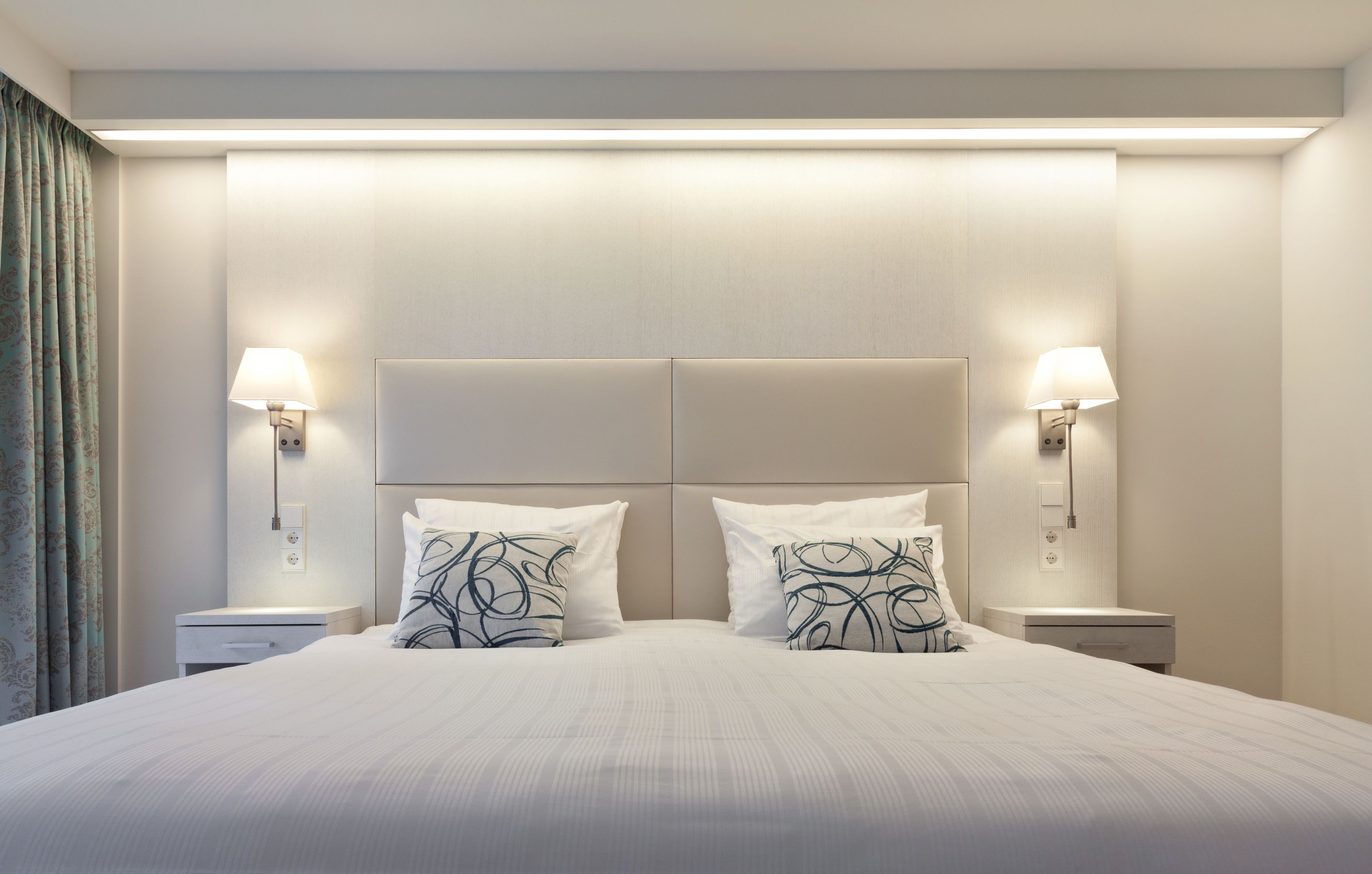 Ein Hotelzimmer mit einem großen Bett, zwei Nachttischen und zwei Wandlampen.