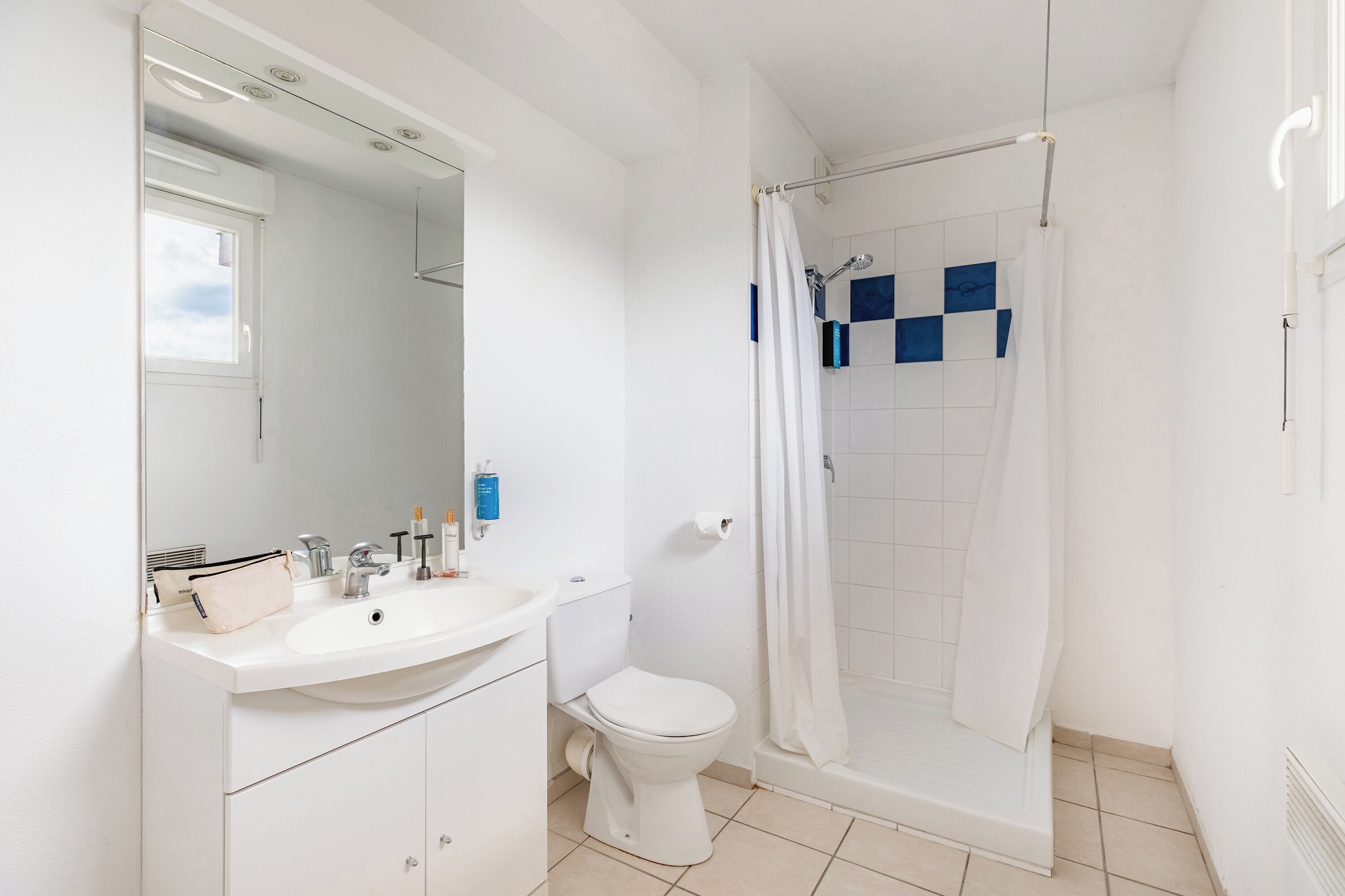 A bathroom with a white sink, toilet, and shower.