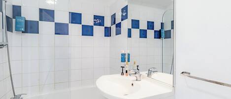 Un baño moderno con bañera, lavamanos y un espejo grande.